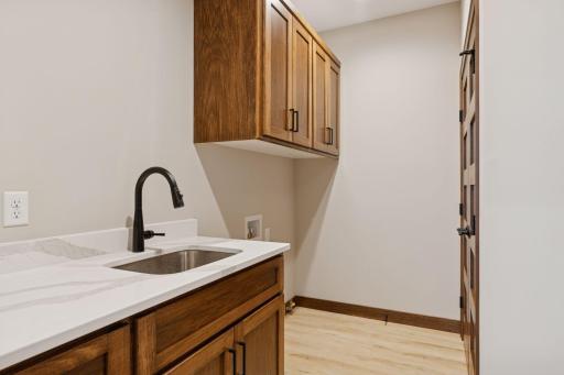 Large laundry room conveniently located just inside the garage. Room features auto lighting, upper and lower cabinets, sink and closet.