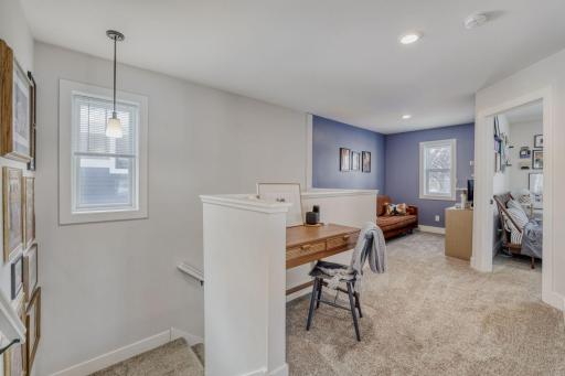 The second floor is carpeted and offers this bonus space at the top of the stairs, staged here as the home office.