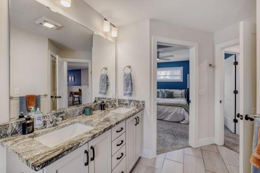 The bathroom features a granite counter top with a double sink and lots of storage.