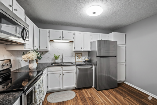 Updated spacious kitchen with stainless steel appliances, stone counter-tops, and tiled backsplash- virtually staged