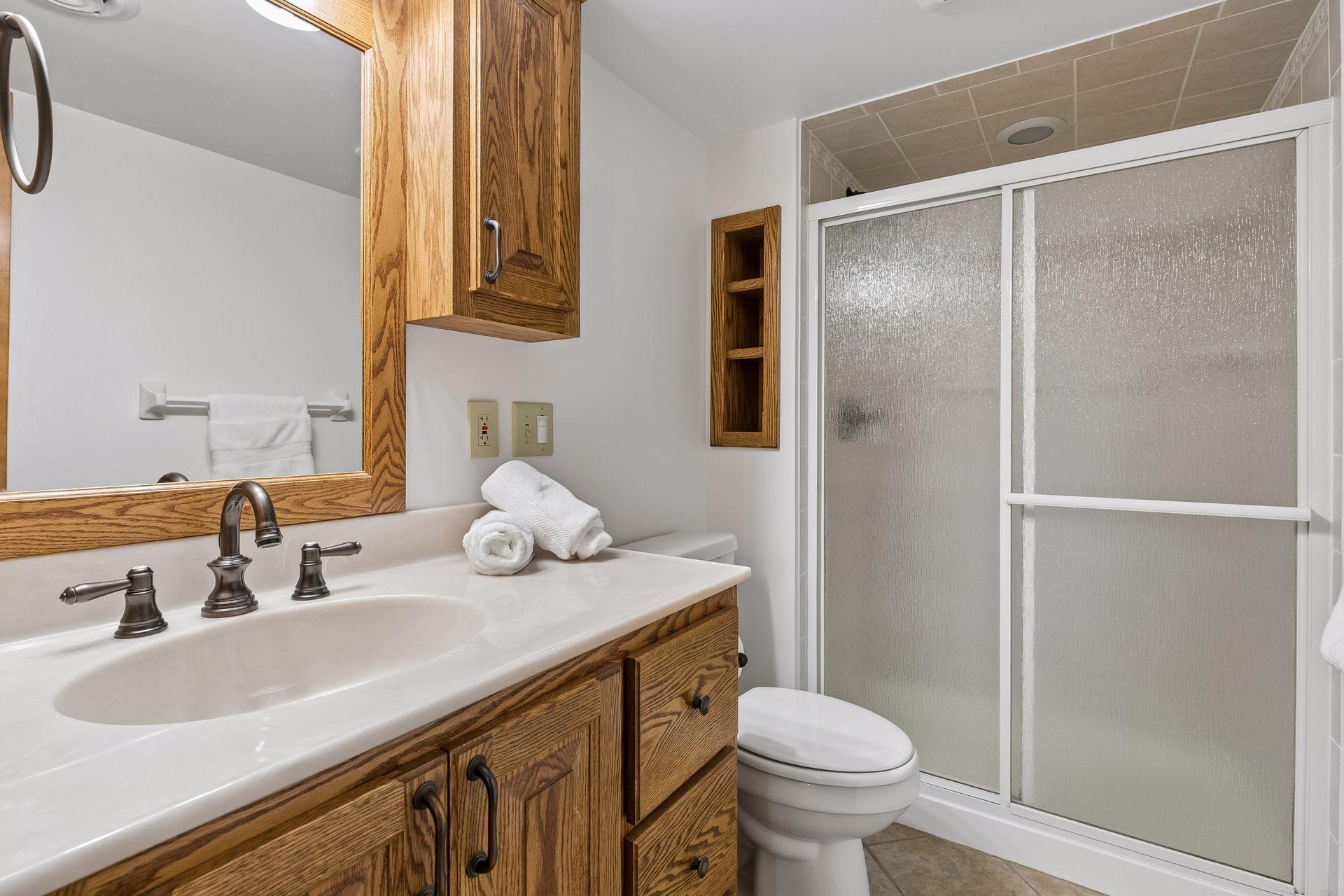 Lower-level 3/4 bathroom with walk-in shower, vanity and plenty of storage space for everyday convenience.