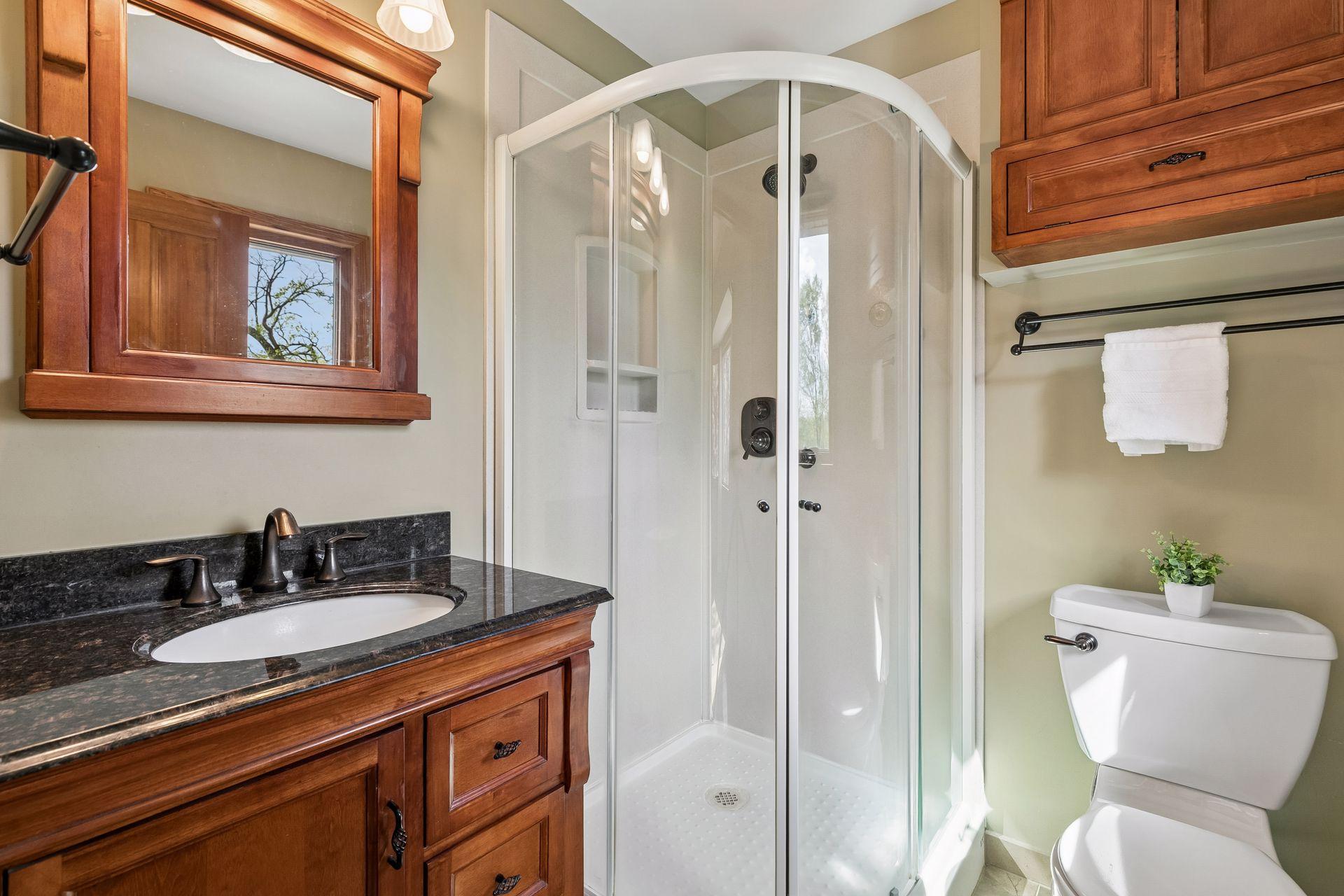 Updated private primary bathroom featuring custom wood vanity, quartz countertops, walk-in shower, and modern finishes creating a clean and stylish spa-like feel.