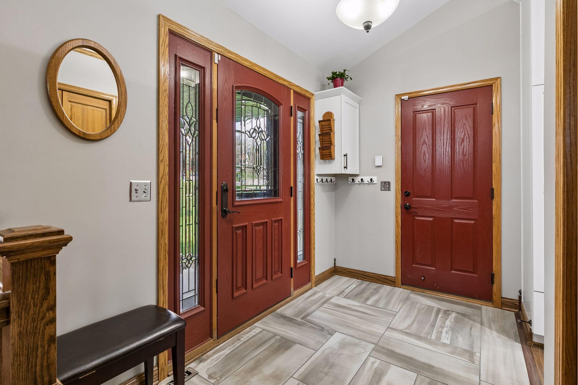 Welcoming front entry with updated flooring, natural wood trim, and decorative glass front door creating a warm first impression for guests and everyday living.
