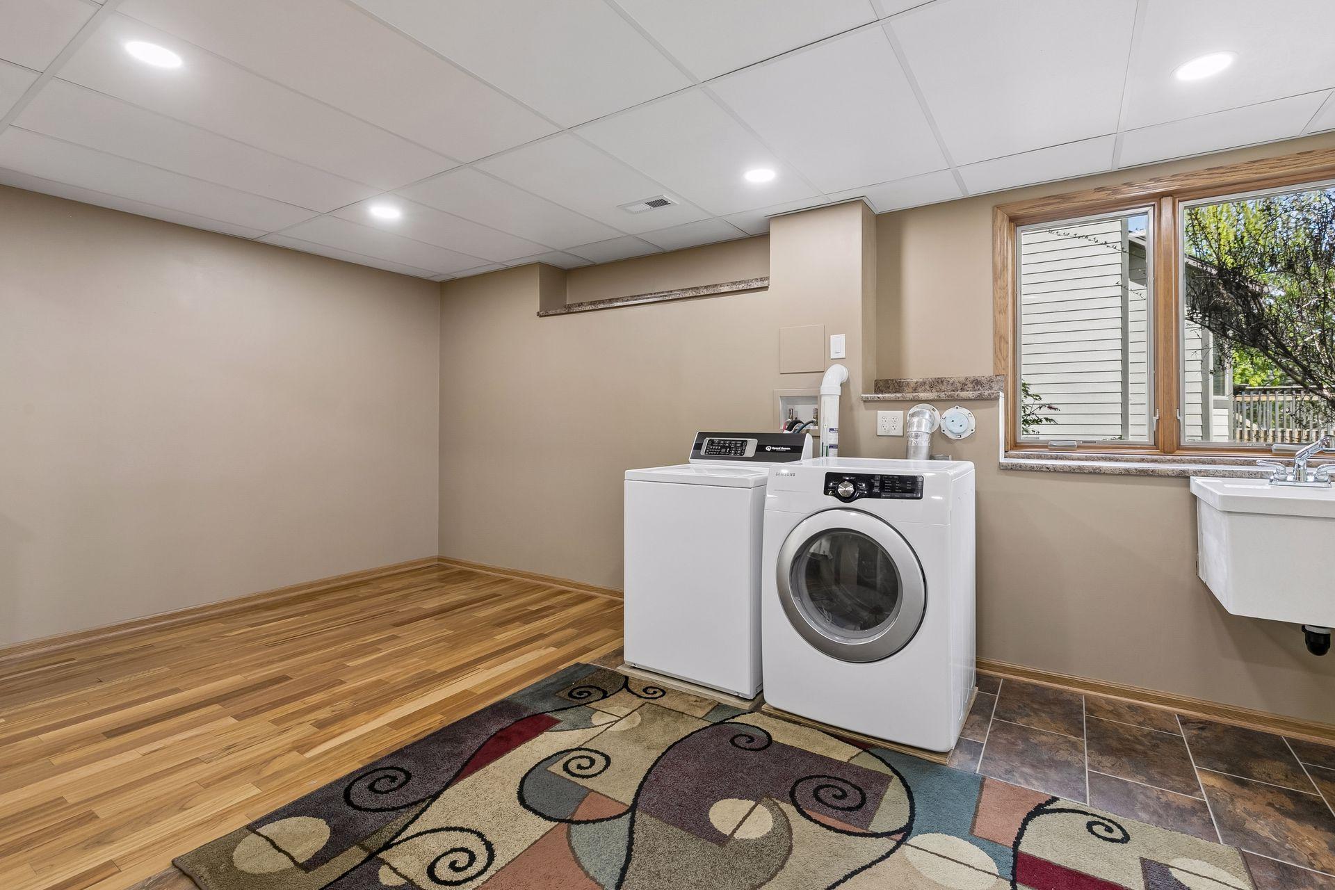 Large lower-level laundry and utility room with extra workspace, storage potential, utility sink, and room for hobbies, crafts or a home gym setup.