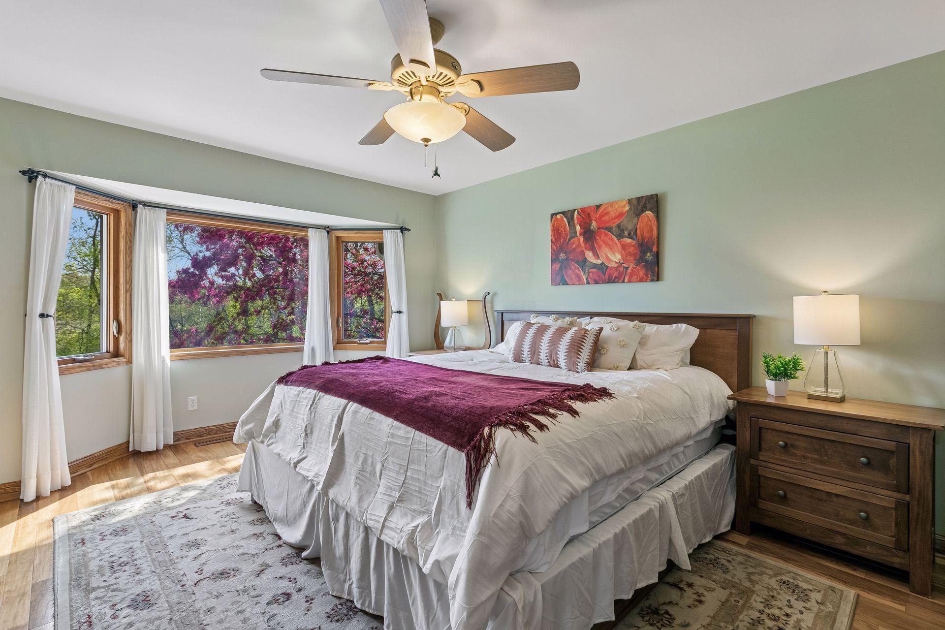 Private primary bedroom retreat with bay window overlooking the backyard, mature trees, and seasonal blooming views, offering comfort, privacy and natural light.