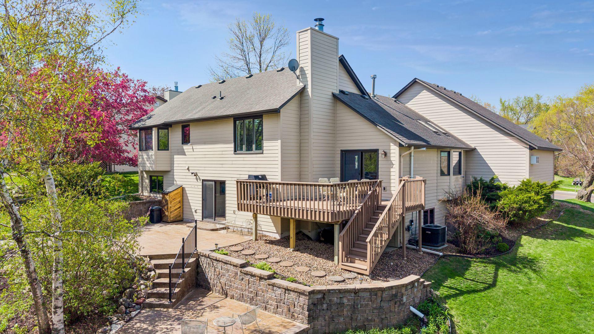 Beautiful exterior rear view featuring maintenance-free deck, walkout lower level, professionally landscaped yard and multiple outdoor entertaining spaces.