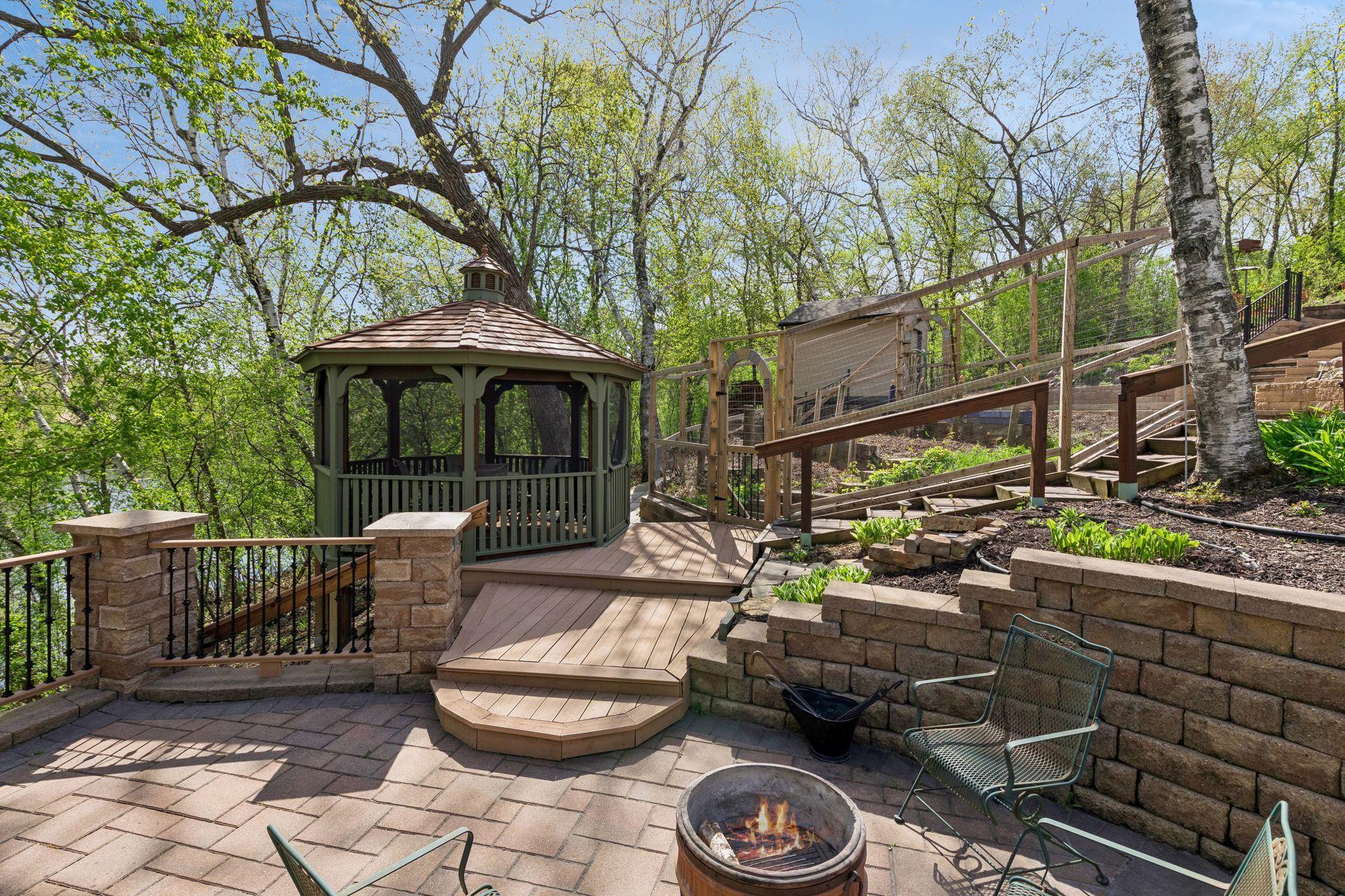 Custom gazebo and outdoor entertaining area with beautiful wooded views, extensive landscaping, and peaceful backyard setting that feels like your own private park.