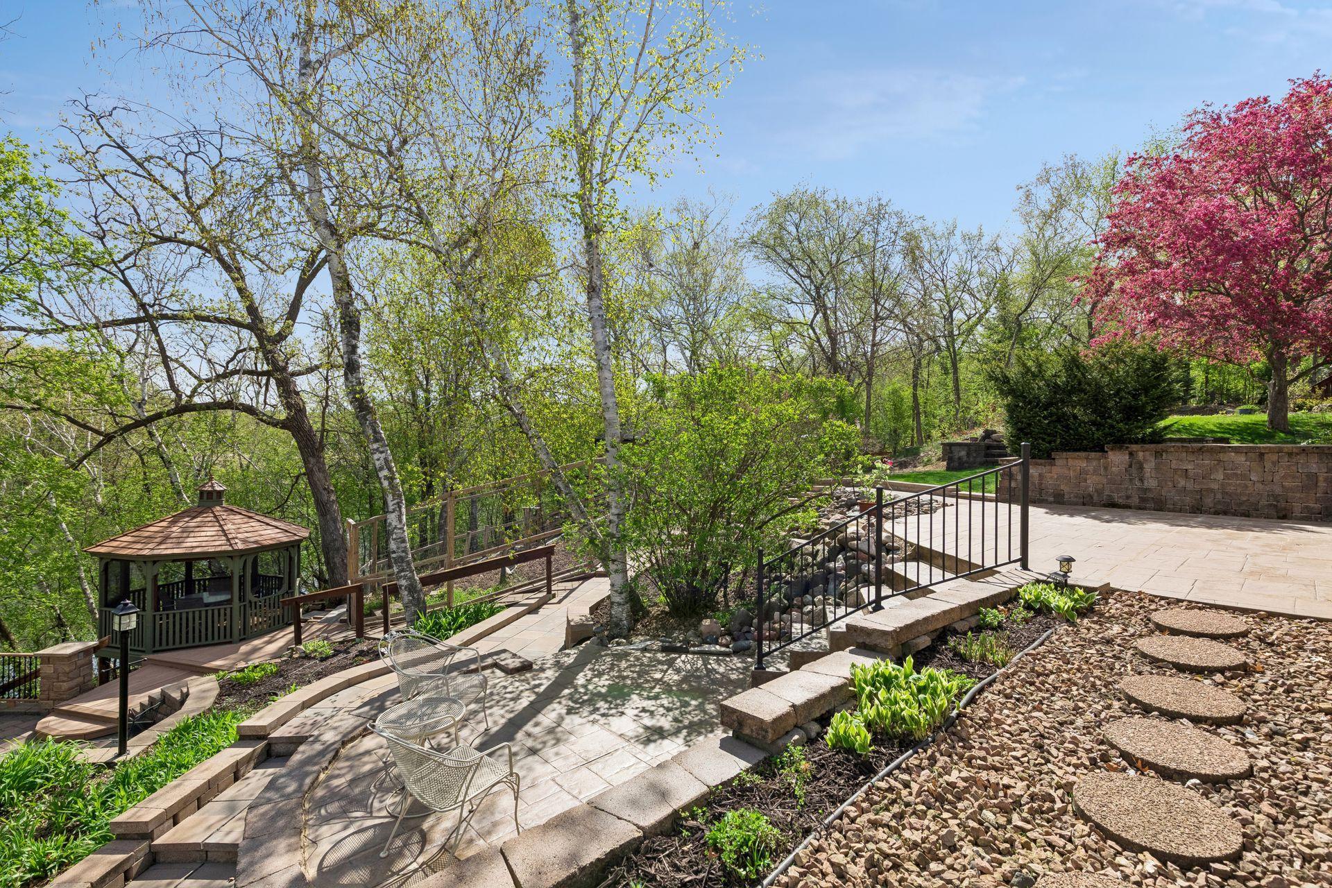 Stunning multi-level outdoor living space with paver patio, retaining walls, firepit area, and scenic wooded surroundings. A rare backyard setup for entertaining and enjoying nature.