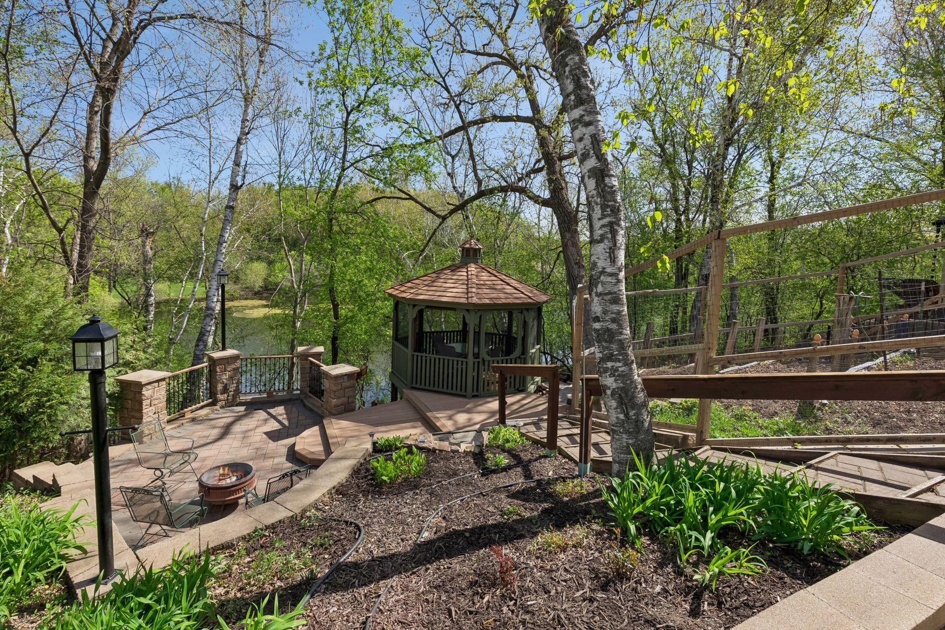 Backyard gazebo overlooking wooded views and pond area, connected by custom walkways and landscaped terraces for a true private outdoor retreat.