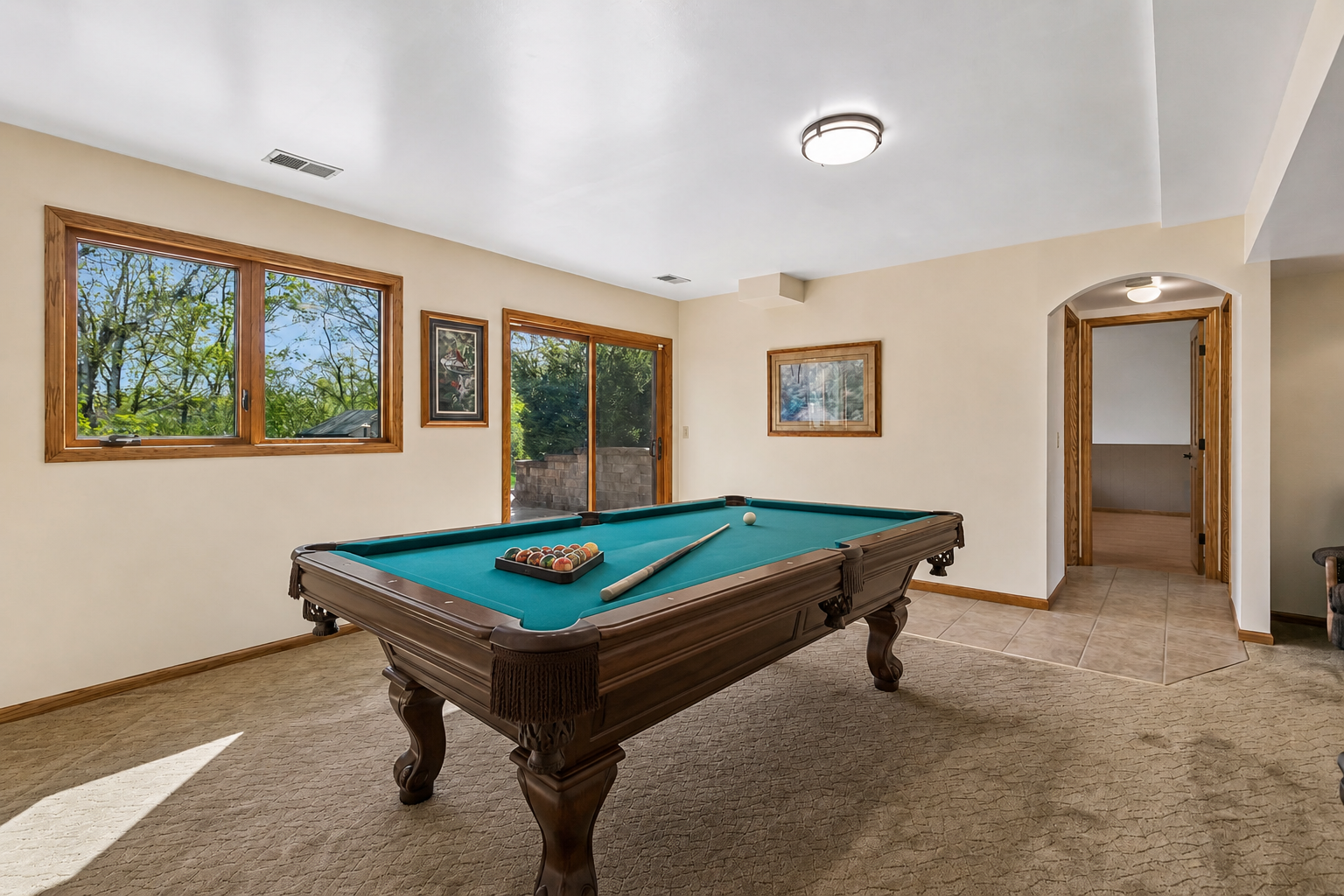 Bright walkout lower-level family room with large windows, and sliding glass door leading to the patio and backyard. Plenty of space for entertaining, movie nights, or adding your pool table and enjoying the space. Virtual staged.