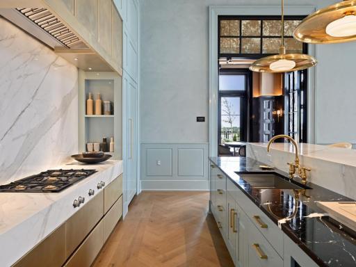 Sleek kitchen design with gas range, marble backsplash, and ample storage.