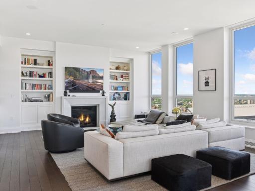 Bright living room with fireplace, custom built-ins, and floor-to-ceiling windows.