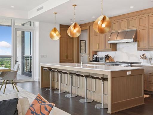 Spacious island with seating for five, designer lighting, and open flow to dining area.