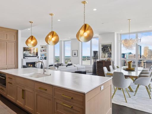 Kitchen seamlessly connects to dining and living spaces with skyline views.