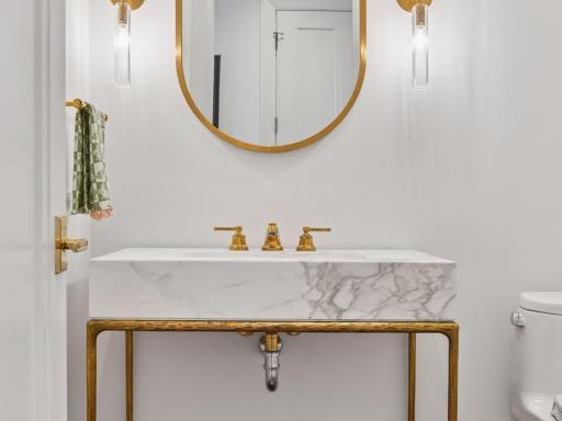 Elegant powder room with marble vanity and gold accents.
