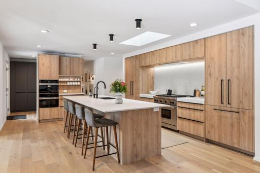 Sleek quartz countertops with subtly veined surfaces complement natural wood tones.
