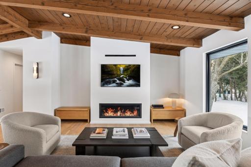 Vaulted wood ceilings with exposed beams create organic modern warmth. The Dramatic fireplace wall with minimalist linear design is a truly stunning!