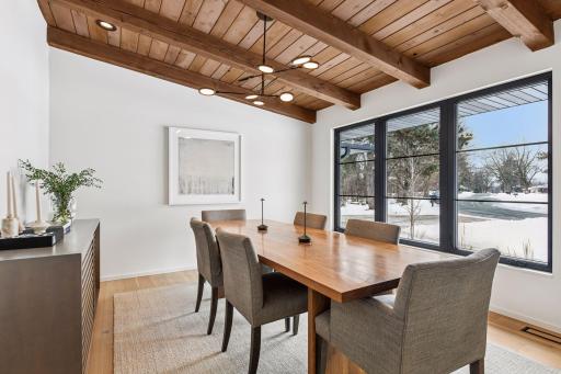 Expansive floor-to-ceiling windows frame this sophisticated dining room in natural light beneath dramatic vaulted ceilings. This generously proportioned space effortlessly accommodates seating for ten.