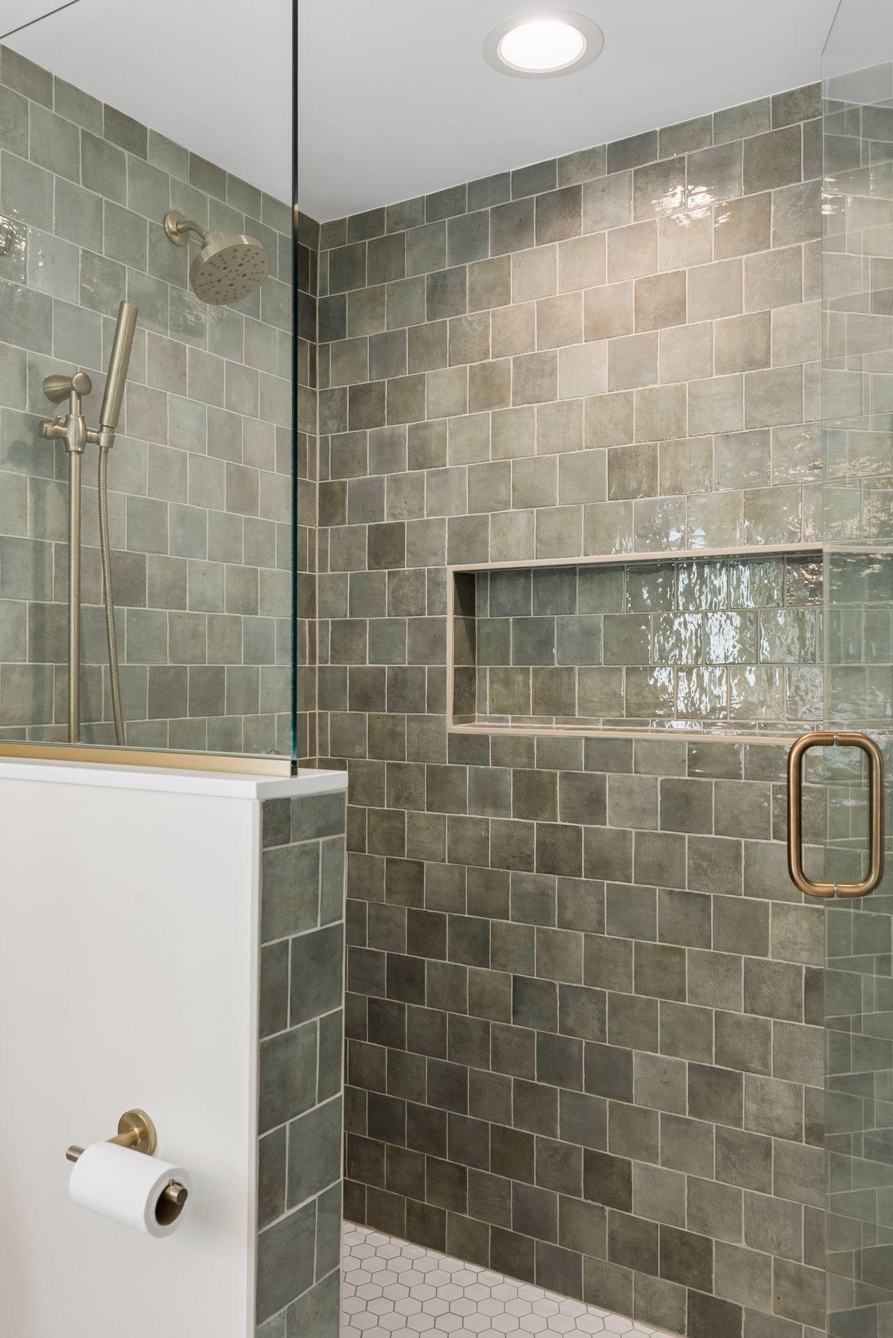 Luxurious floor-to-ceiling tiled shower with alcove ledge and frameless glass door.