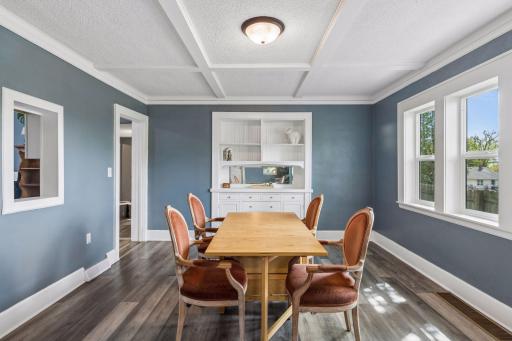 Spacious dining room featuring the original built-in buffet, coffered ceiling, cut-out to kitchen and 3 brand new west facing windows.