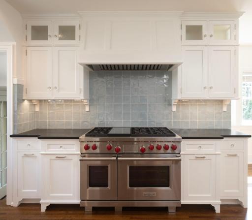 Custom enameled cabinetry, handmade British tile backsplash, custom hood over gas range