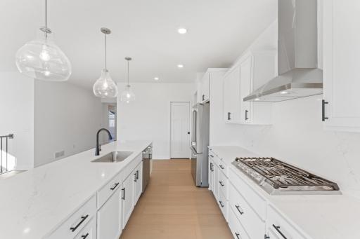 (Photo of an inventory home, actual homes finishes will vary) The gourmet kitchen features a large center island, quartz countertops, LVP floors, stainless steel appliances, and more.