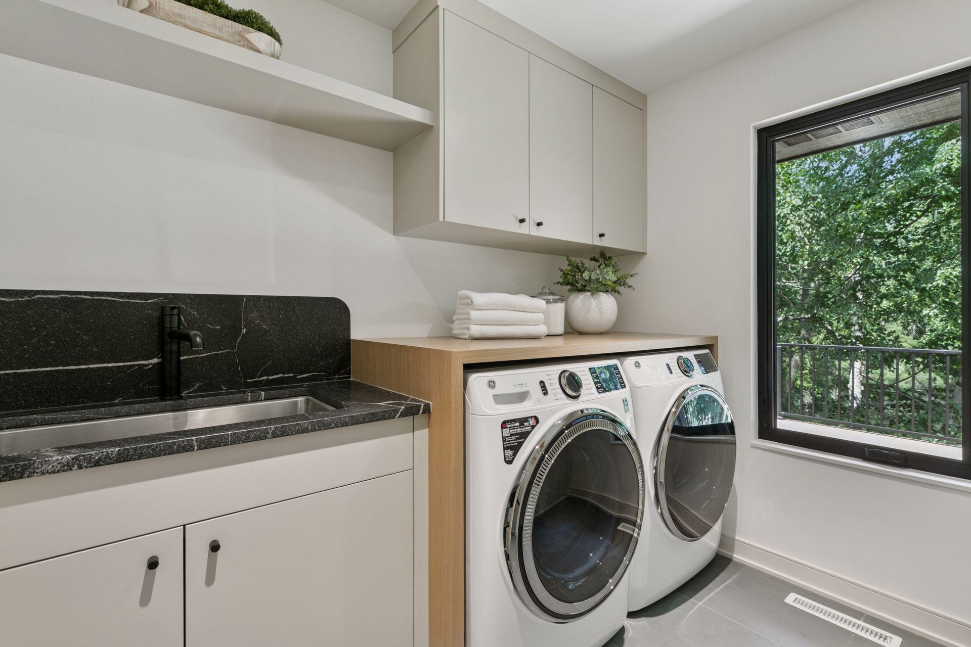 The main level laundry is an experience complete with a white oak countertop with natural oil finish, custom cabinetry, stone wash sink and Montauk Blue Slate Floors