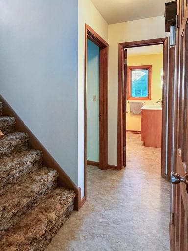 Main floor hallway with staircase and main floor bath in the background