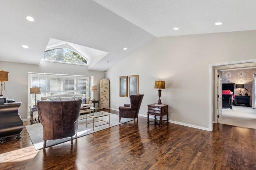 Open-concept main-level living room featuring hardwood floors and soaring vaulted ceilings.