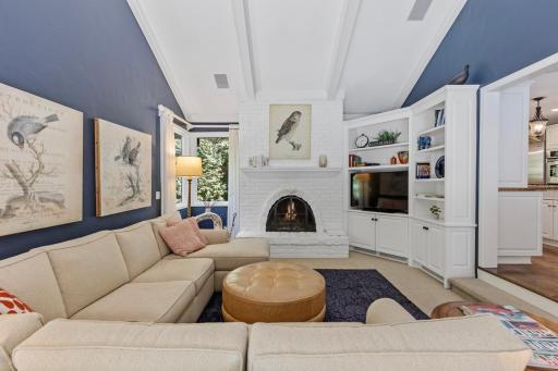 Large main-level family room with vaulted ceilings and a cozy, brick, wood-burning fireplace.