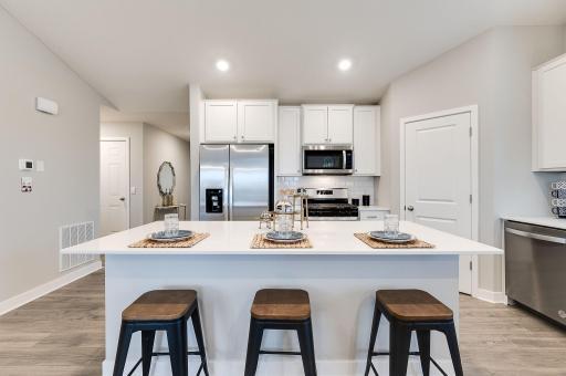 A true designer kitchen; Quartz countertops complimented by tile backsplash, a massive island, plenty of cabinet space, plus a walk-in pantry! Photo of model, colors and options will vary.