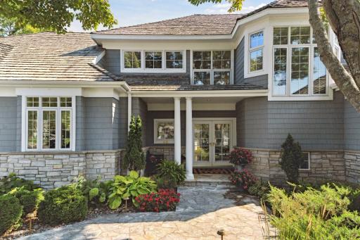 A flagstone sidewalk leads to the main door which has been recessed to shelter guests from inclement weather.