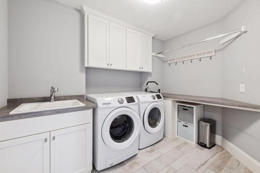 2nd floor laundry with sink and custom cabinets with folding area