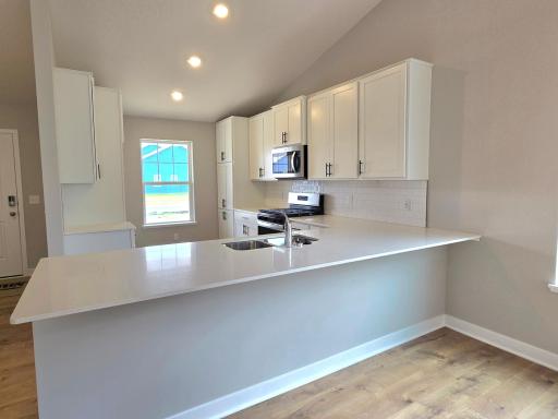 This is a photo of the actual home which has white cabinets, classic white subway tiles and white quartz counters!