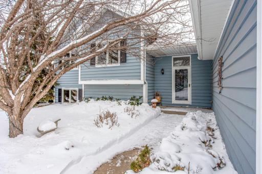 Inviting front entryway with covered access, surrounded by established landscaping and mature trees for added character and privacy.