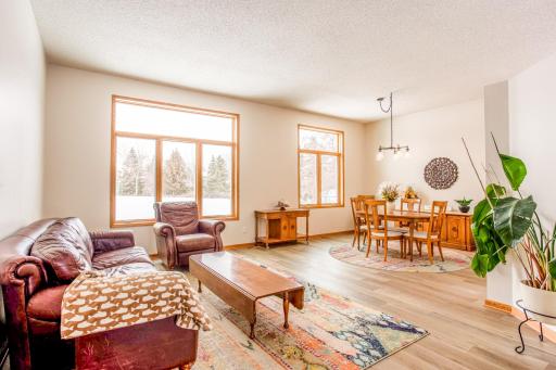 Spacious and light-filled living and dining area with large windows, creating a warm and welcoming atmosphere.