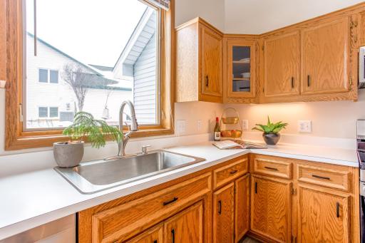Bright farmhouse sink with large window views, complemented by generous counter space and classic wood cabinetry.