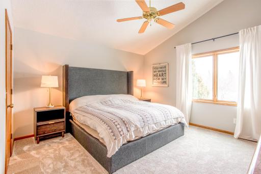 Spacious primary bedroom featuring vaulted ceilings, soft natural light, and a calming, neutral color palette.