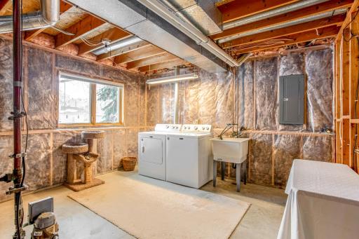 Spacious laundry area with utility sink and additional room for storage or workspace.