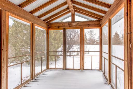 Inviting screened porch with wood accents and panoramic views of the backyardâideal for enjoying the outdoors in comfort.