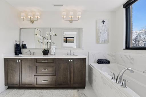 Luxurious spa-like bathroom features double sinks and vanities, and heated tile floors. .