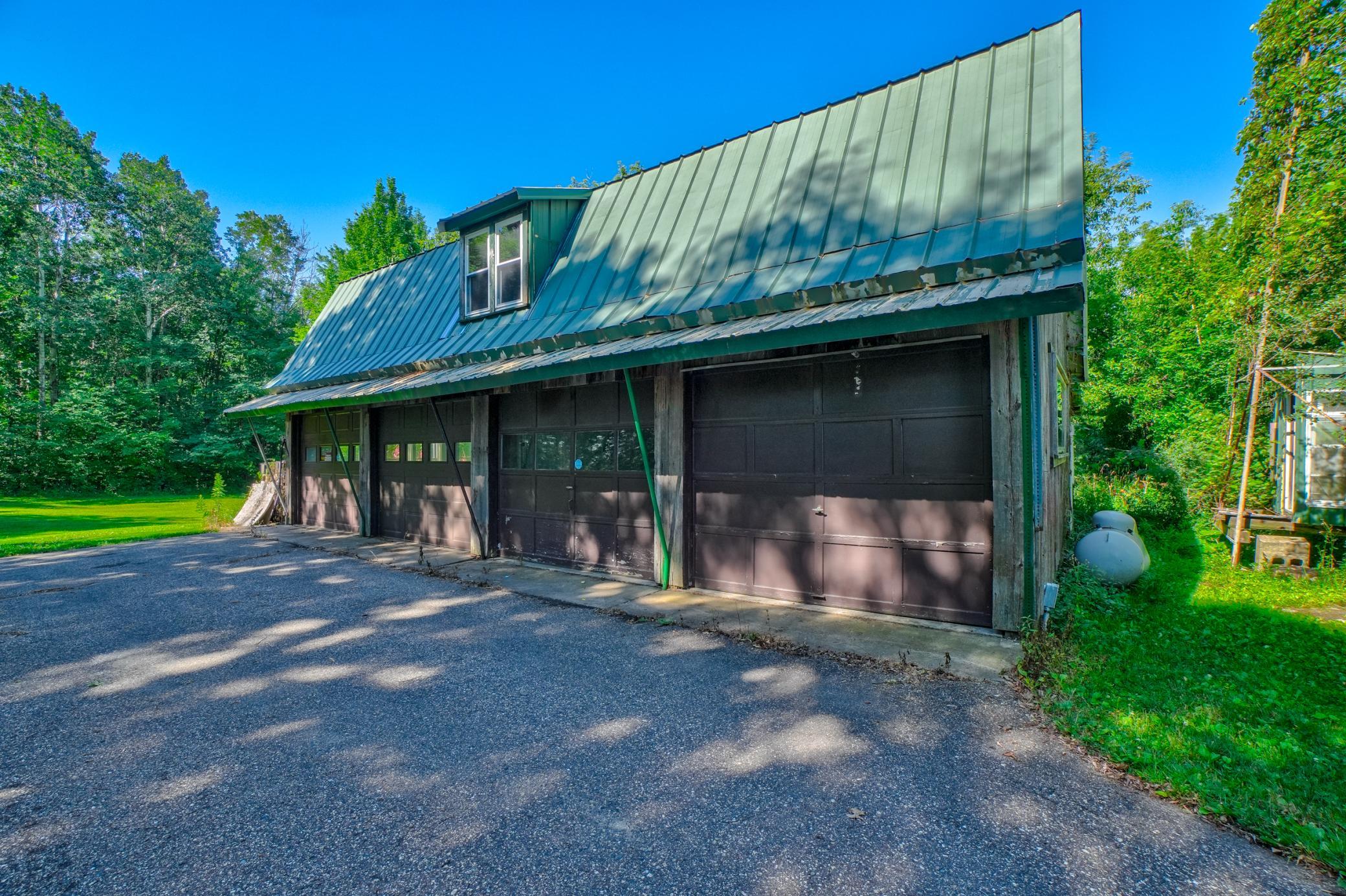 Outside, the possibilities continue with a heated 2-car garage, a spacious heated outbuilding featuring five overhead doors, loft storage, and a wood-burning stove, an additional workshop/storage building with an attached carport, plus a tool shed.