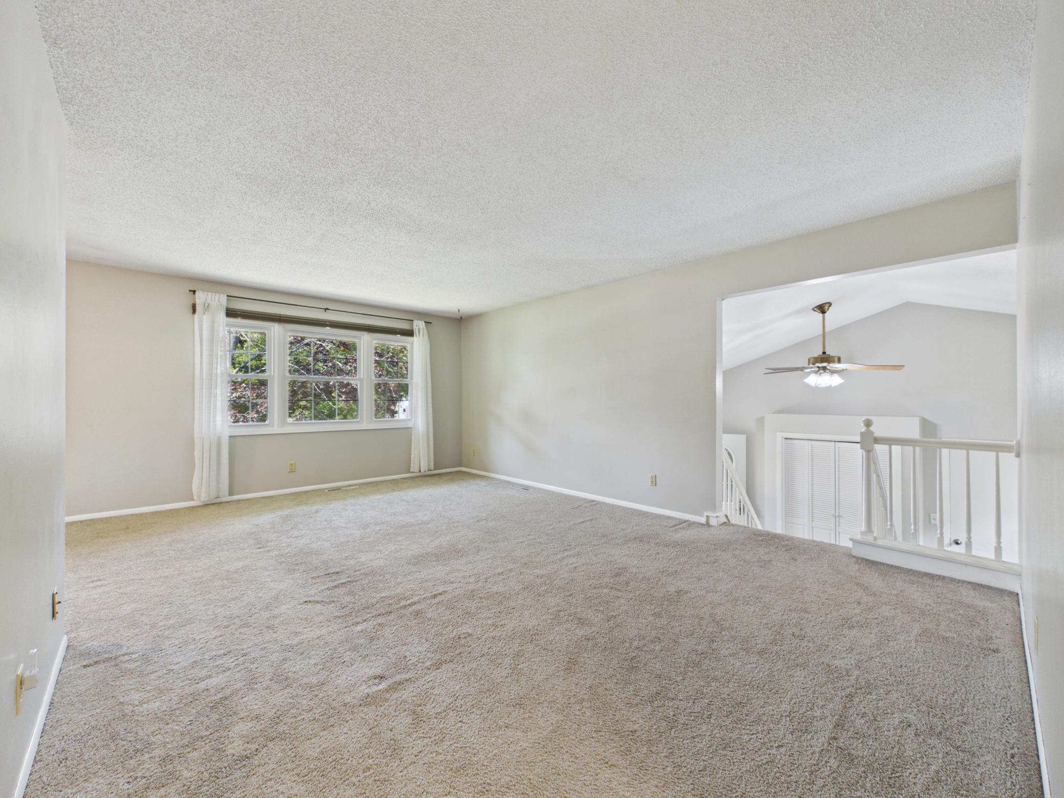 Spacious and welcoming main floor living room with plush carpet, generous room for the whole family, and an open flow into the dining room and kitchen. A warm and comfortable space perfect for everyday living and entertaining alike.