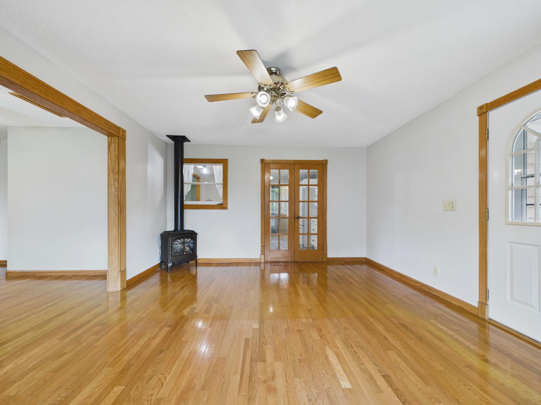 Living room with wood stove and French doors to the kitchen, plus access to a small deck with stairs down to the backyard.