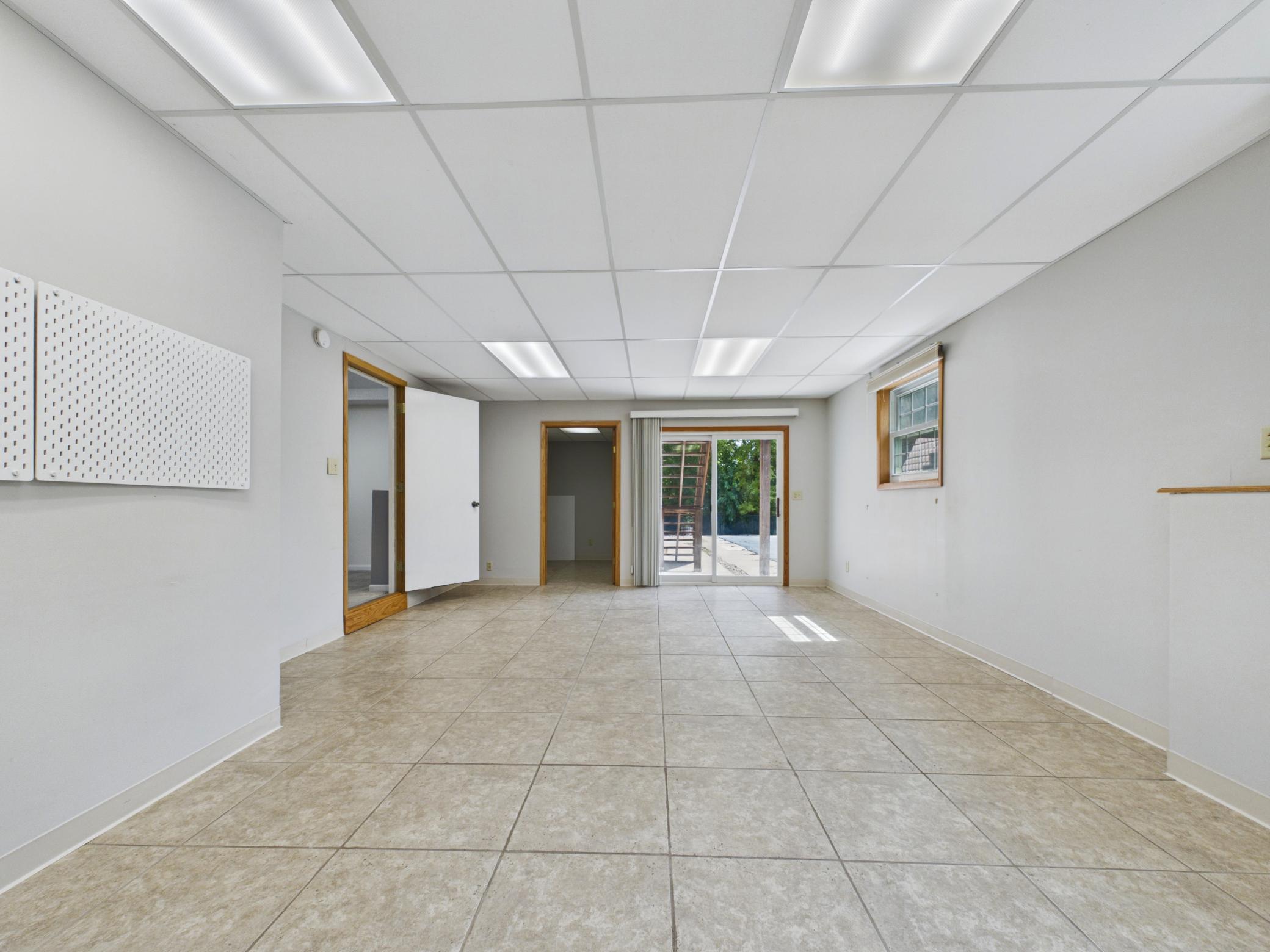 Bright, versatile walkout lower level with tile flooring, egress windows, a cozy stove, and sliding door to the backyard — perfect for a studio, in-law suite, or game room.