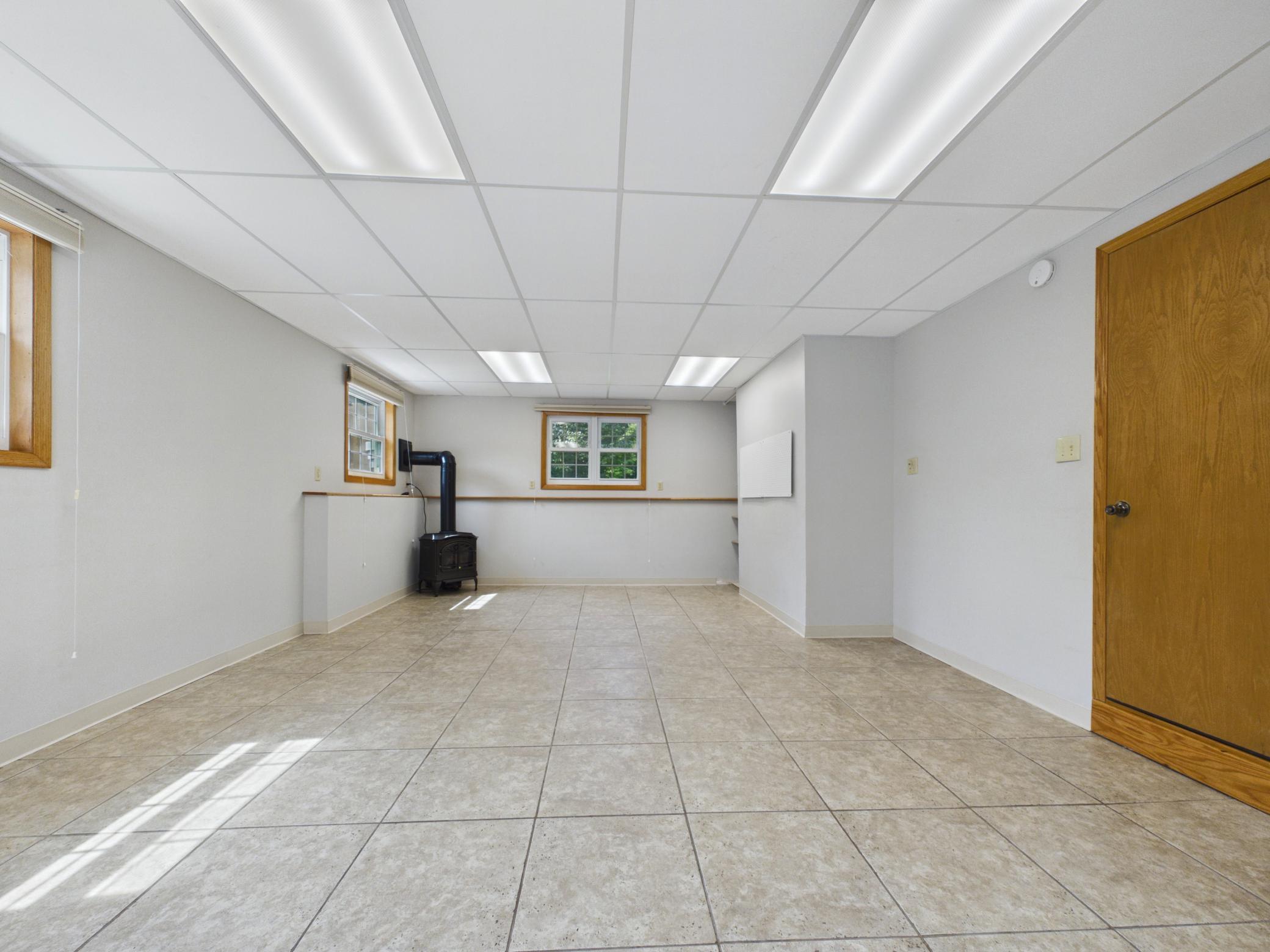 Bright, versatile walkout lower level with tile flooring, egress windows, a cozy stove, and sliding door to the backyard — perfect for a studio, in-law suite, or game room.