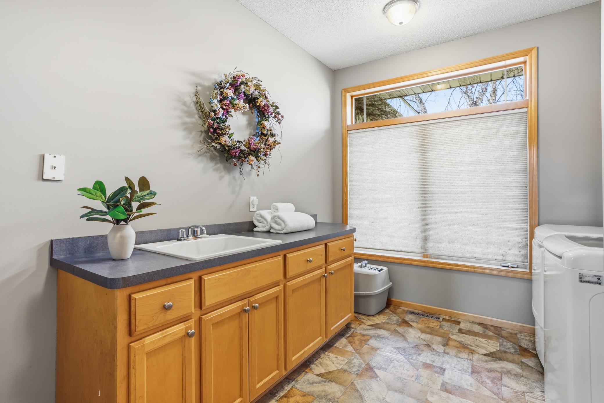 Main level laundry room is spacious and completes the requirements for true one level living! The utility sink and additional countertop space for folding create a functional work space.