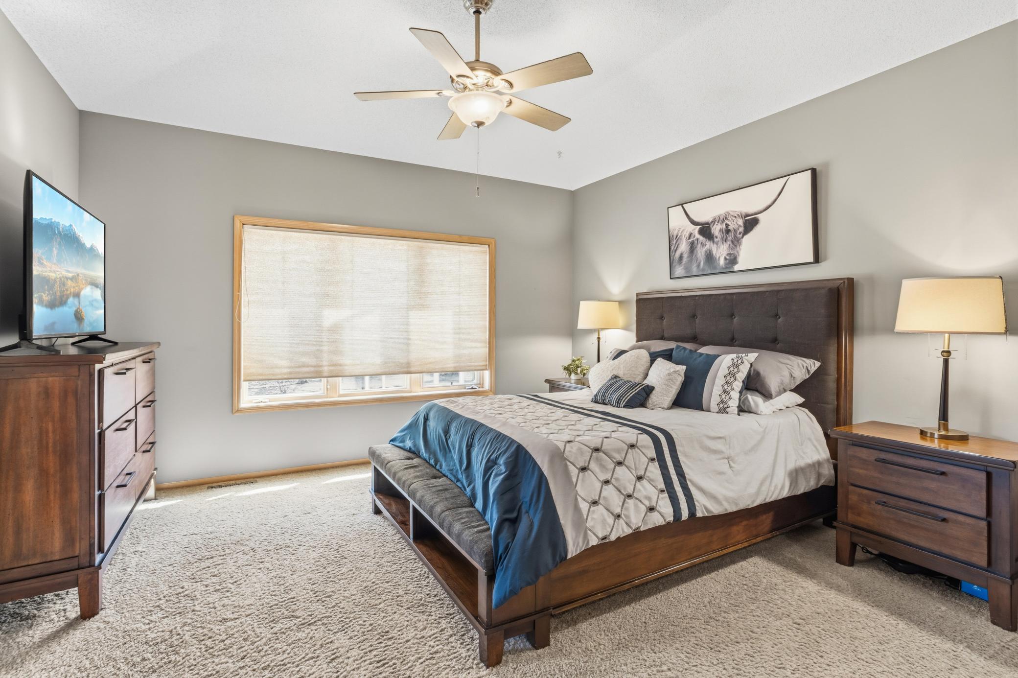 Double doors create an elegant entry into the spacious main-level primary bedroom which offers a peaceful retreat with a tray vaulted ceiling and ceiling fan that add both character and comfort.