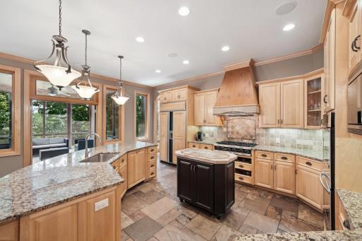 The gourmet kitchen shines with granite counters, slate flooring, a hearth room, and a large breakfast bar that opens to the informal dining area and screen porch.