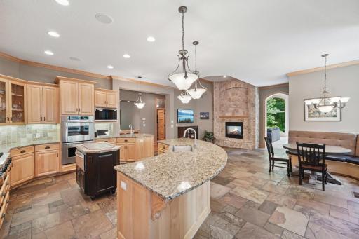 The gourmet kitchen shines with granite counters, slate flooring, a hearth room, and a large breakfast bar that opens to the informal dining area and screen porch.